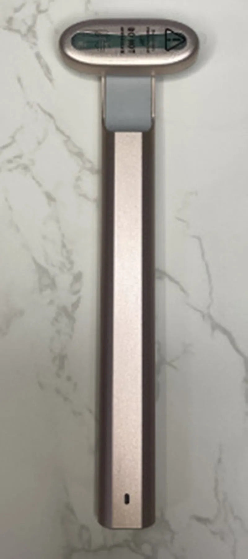 Micro current introduction eye massage instrument in green, with RF gear and USB charging cable on a white background