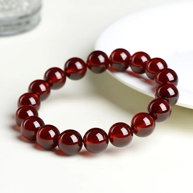 Natural orange red garnet crystal bracelet with ruyi design on a wrist.