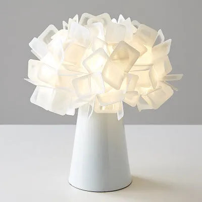Simple Nordic style table lamp with metal base in assorted colours on a wooden table.