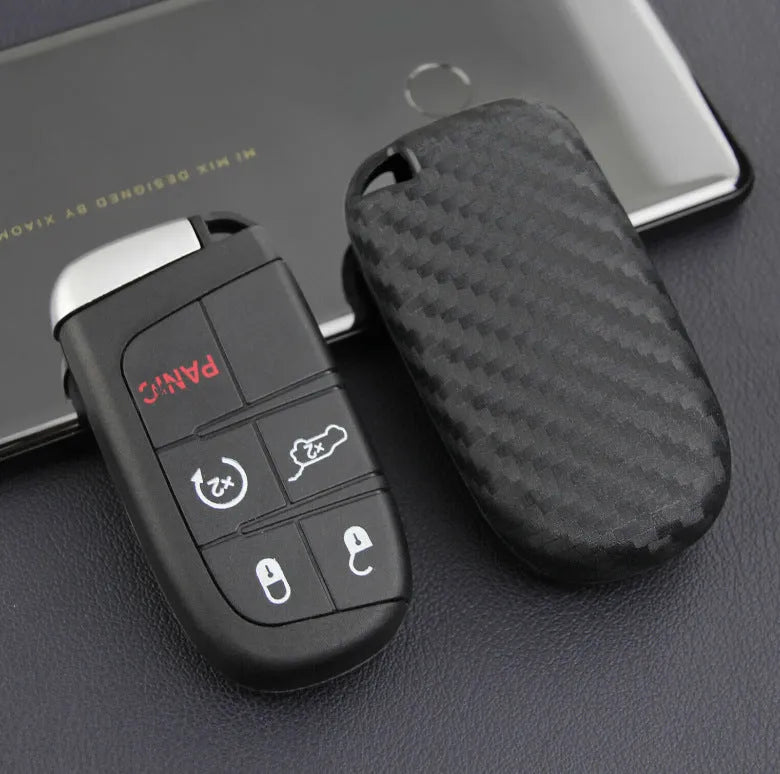 Black silicone protective case covering a Dodge car key fob, shown next to an unbuckled version.