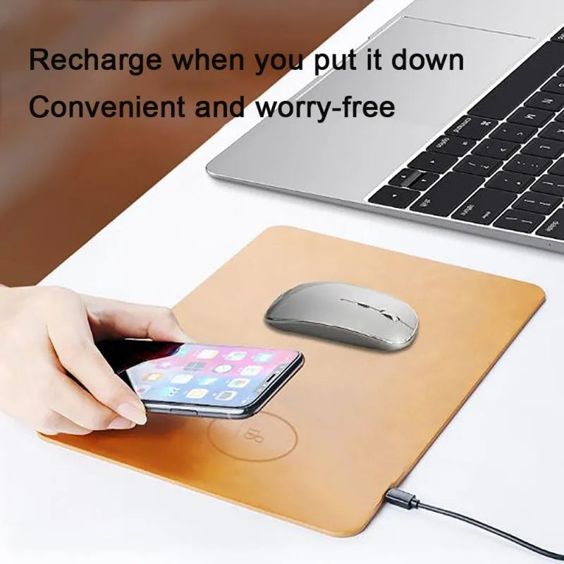 Brown leather wireless charging mouse pad on a wooden desk with a phone charging on it.