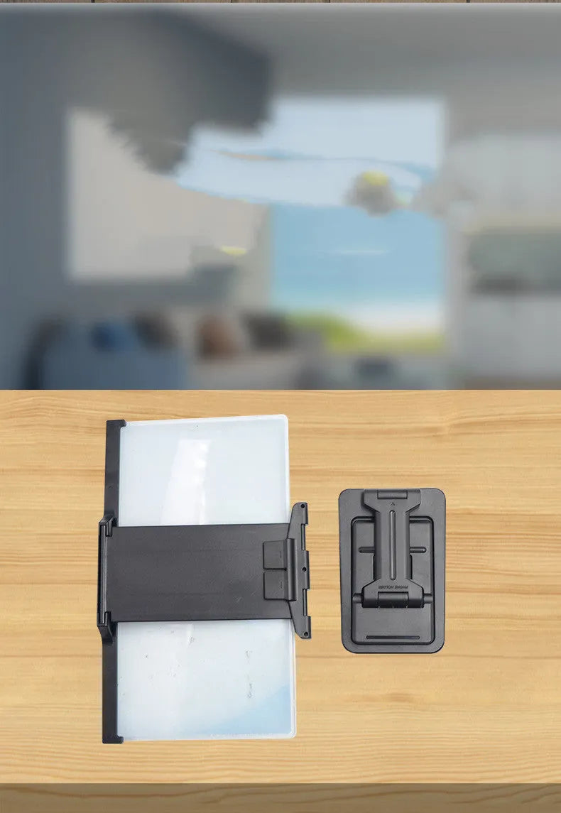 Black foldable mobile phone screen amplifier and detachable holder set up on a desk.
