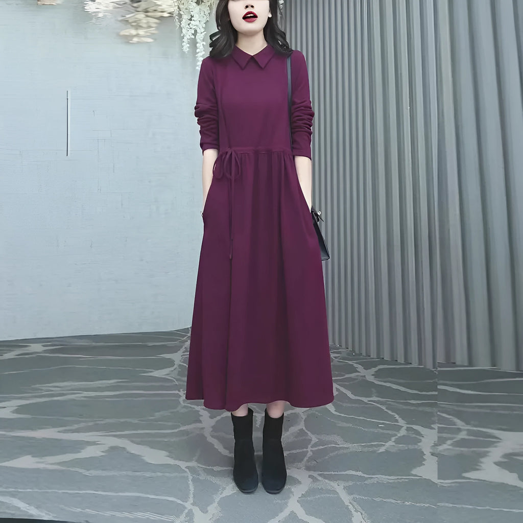 A woman wearing a solid purplish-red long-sleeve maxi dress with extra-long sleeves, suitable for autumn and winter.