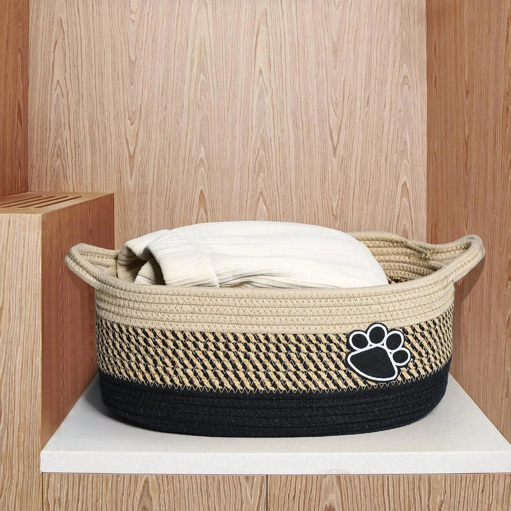 Handwoven light beige cotton rope storage basket with a wooden handle on a table.