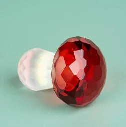 Colourful mushroom-shaped crystal decoration in geometric style on a surface, showing light green hue.