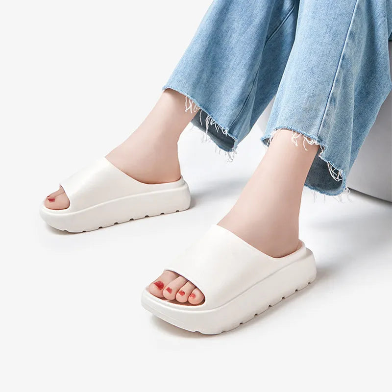 Women's beige fish mouth slippers with a thick light-coloured sole on a wooden floor.
