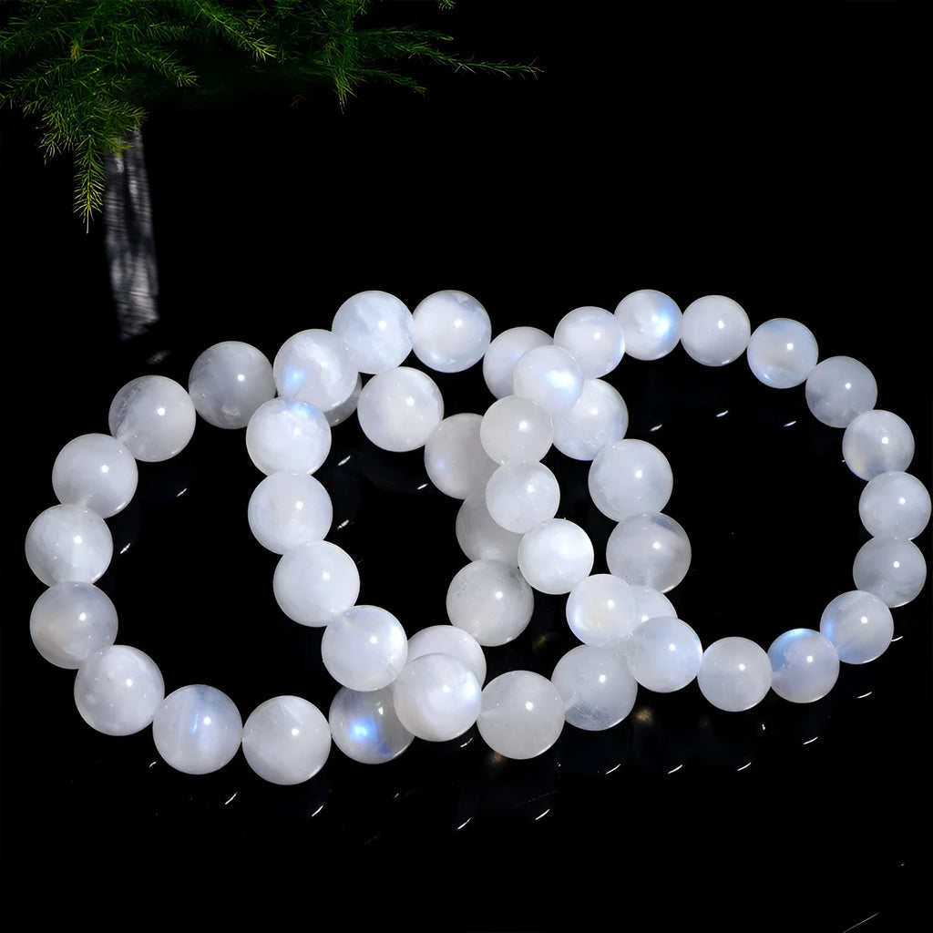 Natural white moonstone bracelet with round polished beads showing a blue sheen, laid flat.