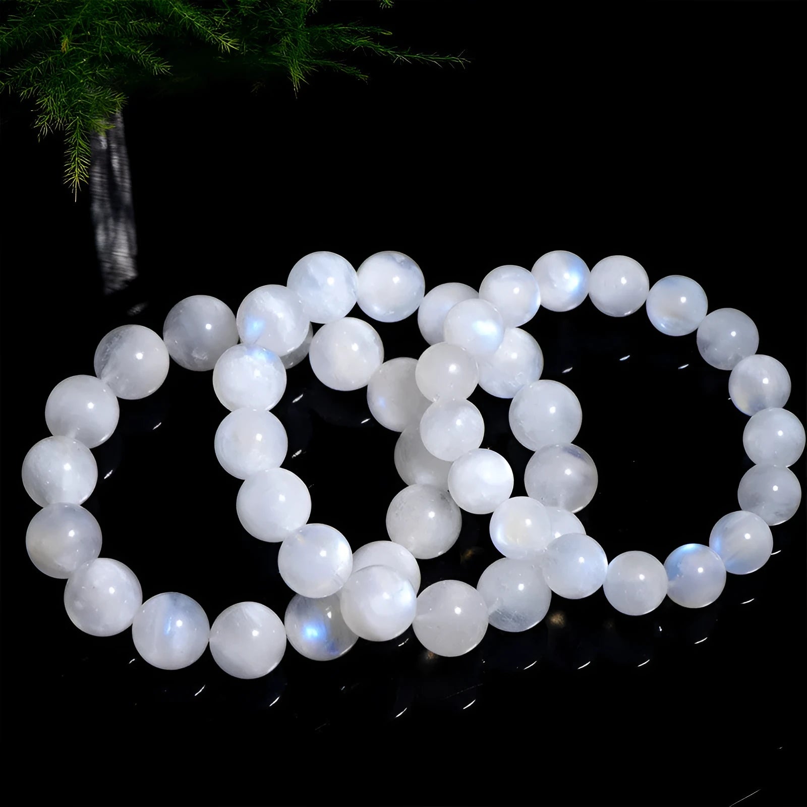 Natural white moonstone bracelet with round polished beads showing a blue sheen, laid flat.