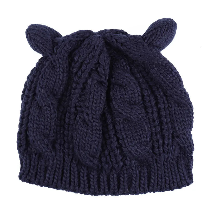 Handmade red knitted beanie with 3D cat ears and a pom pom on a mannequin head
