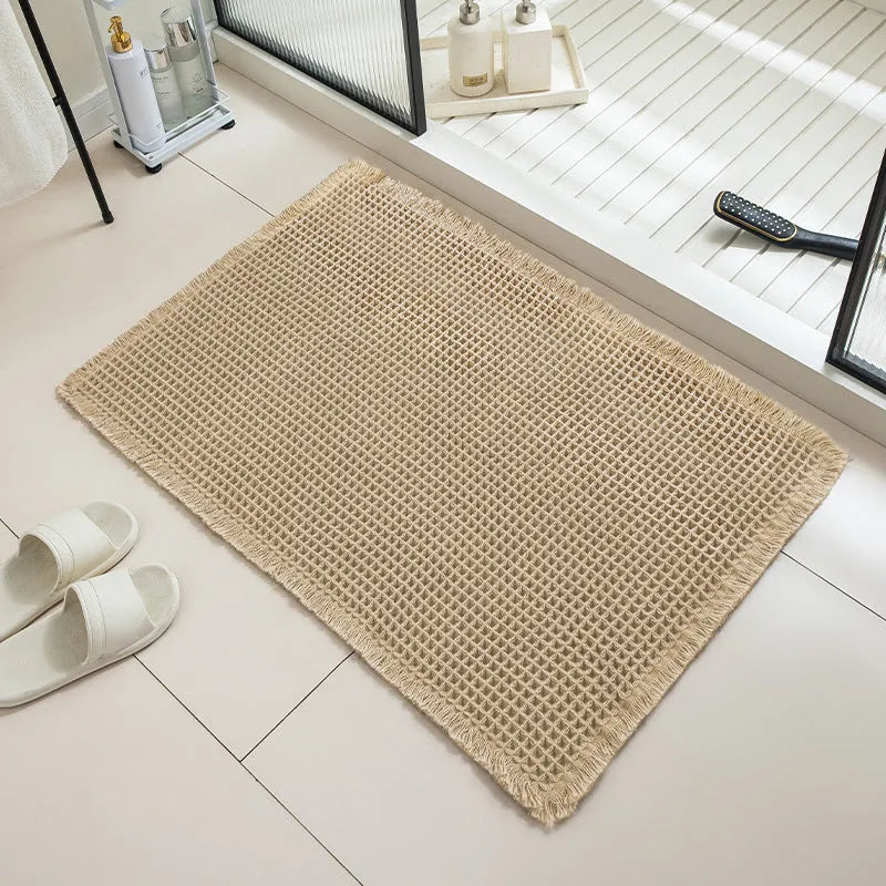A beige checkered non-slip polyester bathroom carpet on a tiled floor.