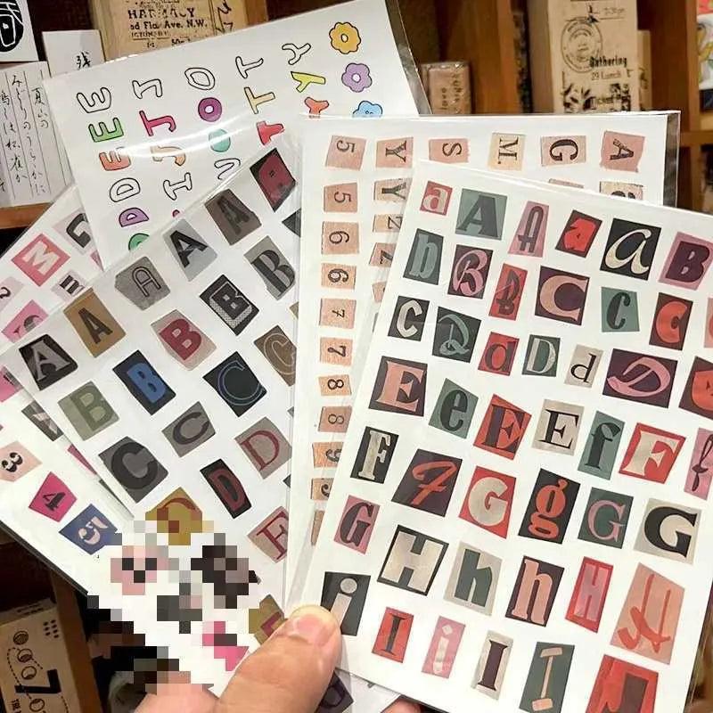 Pack of printed decorative stickers showing English letters, numbers, symbols, and weekly words in a cute style.