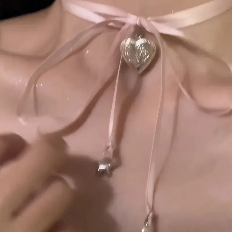 Silver-tone women's necklace with a ribbon love pendant on a delicate clavicle chain.