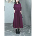 A woman wearing a solid purplish-red long-sleeve maxi dress with extra-long sleeves, suitable for autumn and winter.