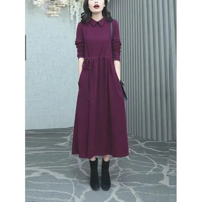 A woman wearing a solid purplish-red long-sleeve maxi dress with extra-long sleeves, suitable for autumn and winter.