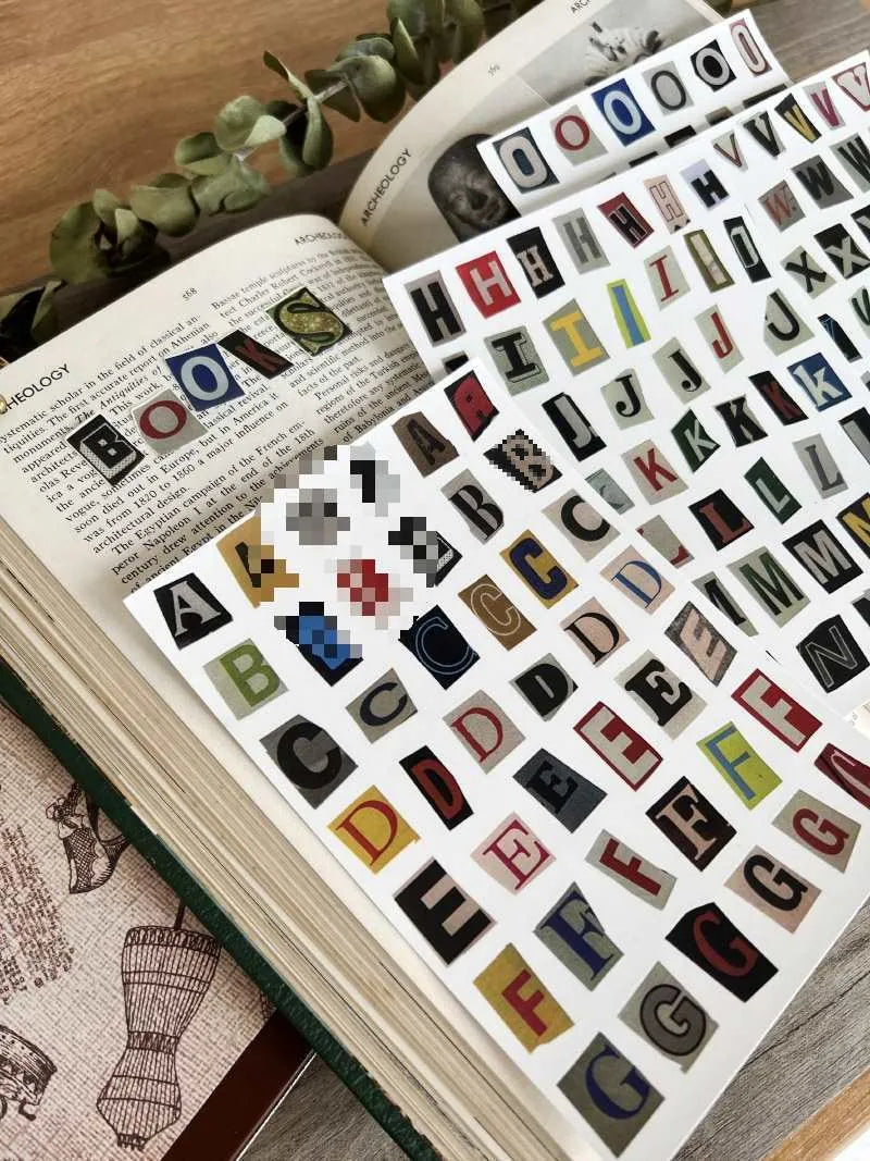 Pack of printed decorative stickers showing English letters, numbers, symbols, and weekly words in a cute style.