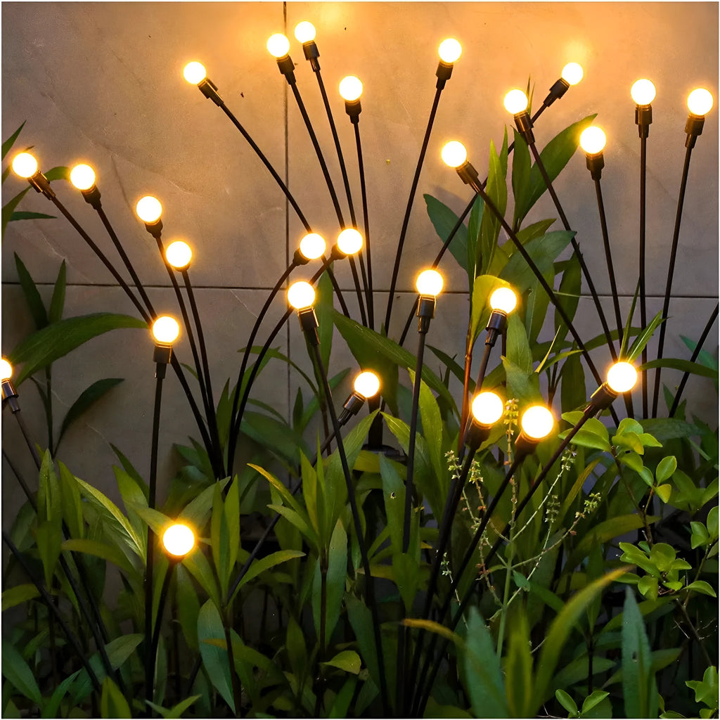 Solar-powered LED garden stake light with automatic sensor, shown pushed into soil beside plants.