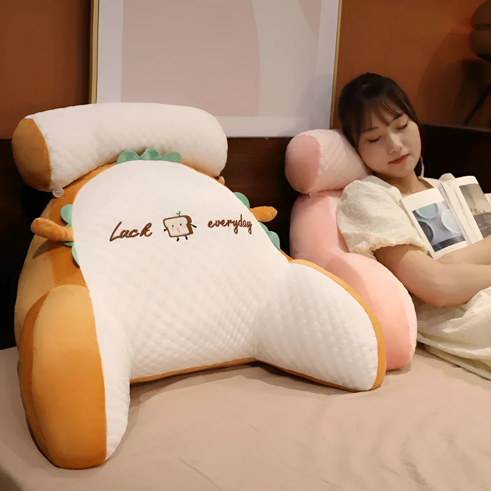Large triangle-shaped reading cushion with embroidered design on a sofa.