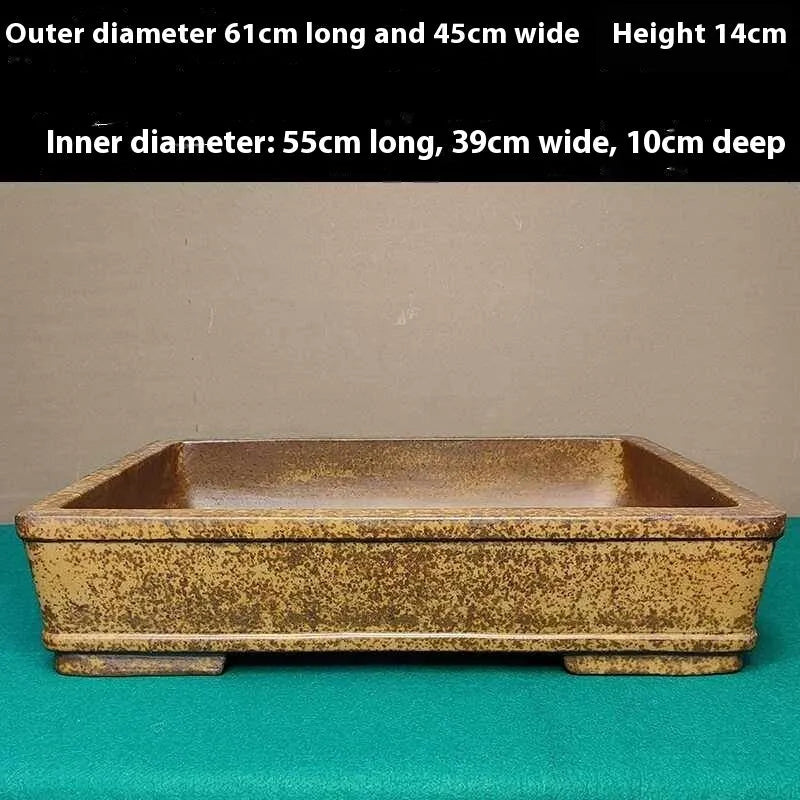 Straight-sided shallow rectangular flower pot made from unglazed Yixing purple sand clay, on a wooden surface.