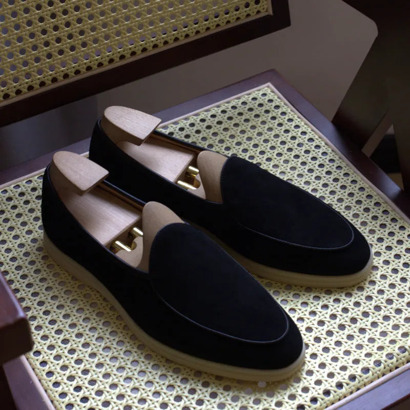 British handmade brown leather men's loafers with a flat TPR sole on a wooden surface.