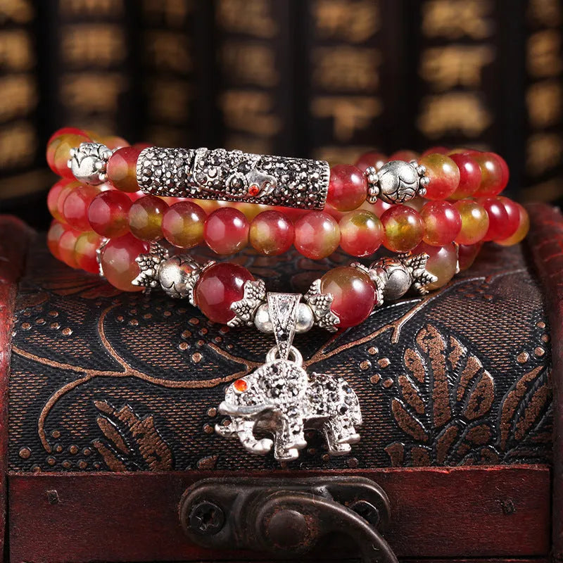 Handmade natural watermelon crystal bracelet with a Chinese knot, showing geometric beads in elephant style.