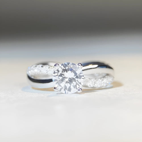 Sterling silver ring with a 1 karat moissanite stone, geometric cross design, and twisted band.