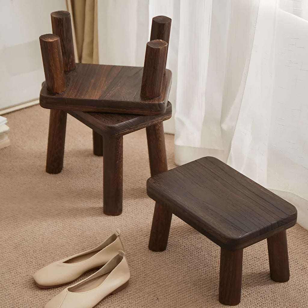 Distressed solid wood household stool for changing shoes in a living room setting.