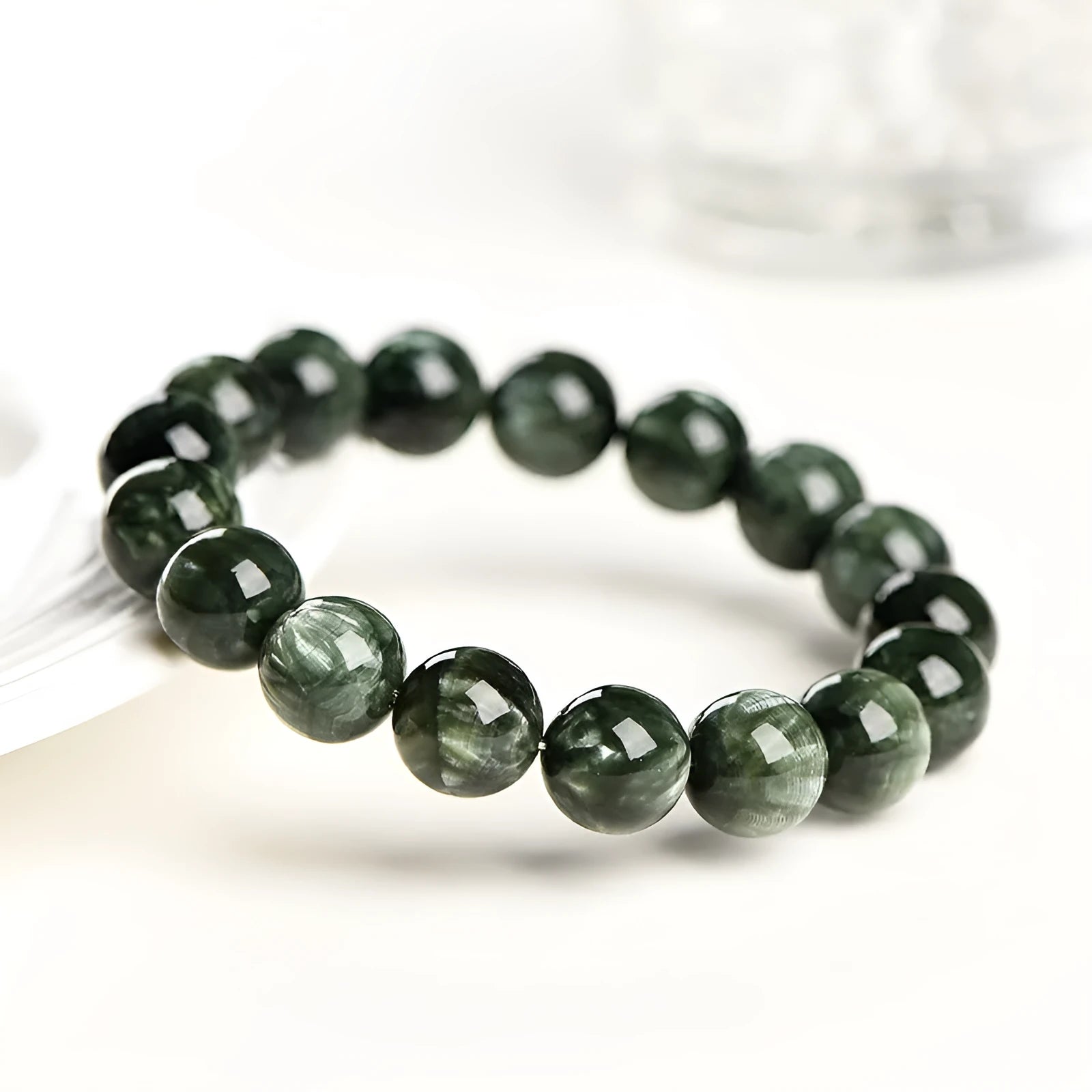 A bracelet made of polished green dragon crystal round beads with a geometric Ruyi design element.