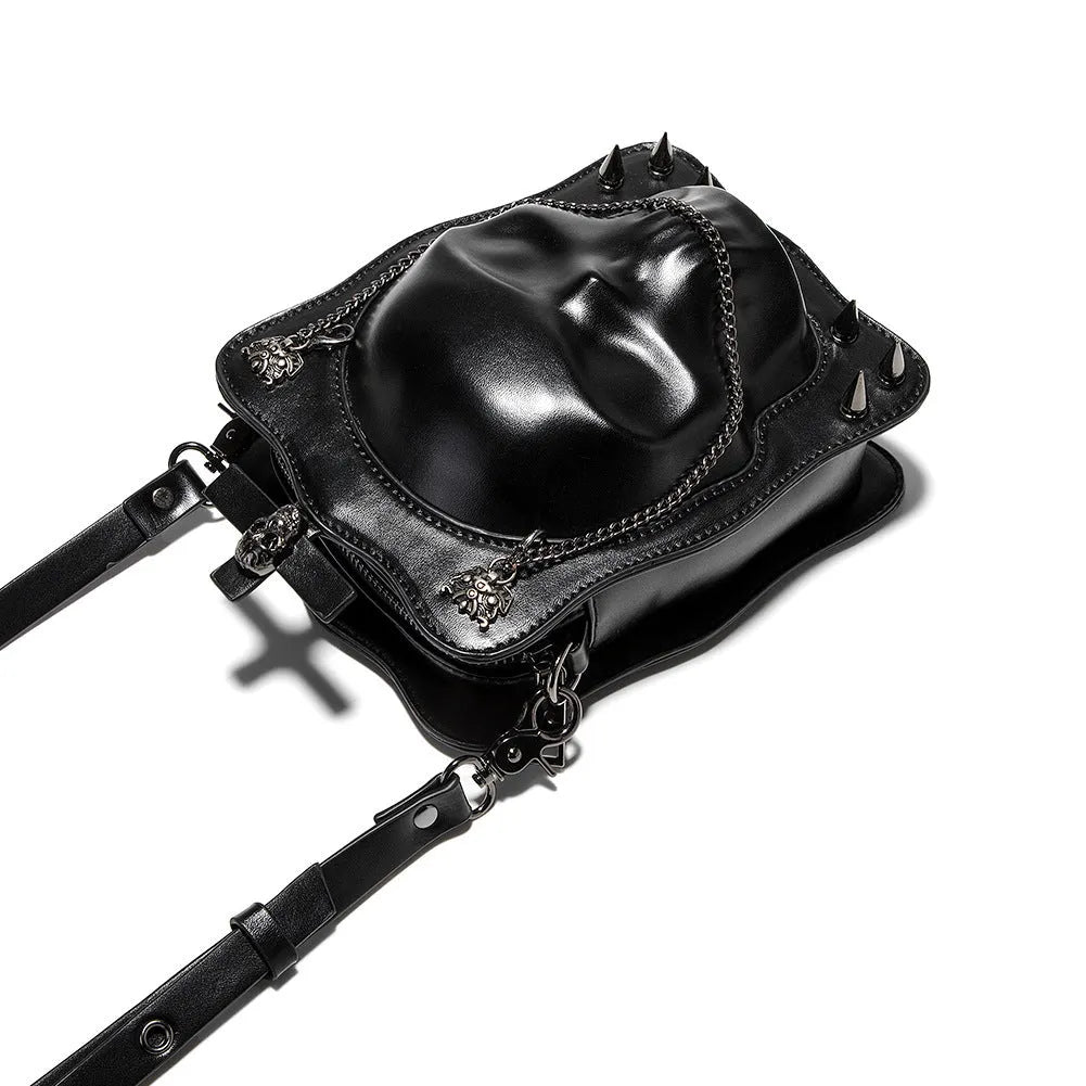 Black mini square crossbody bag with embossed skull design, metal rivets, chain strap, and top zipper.