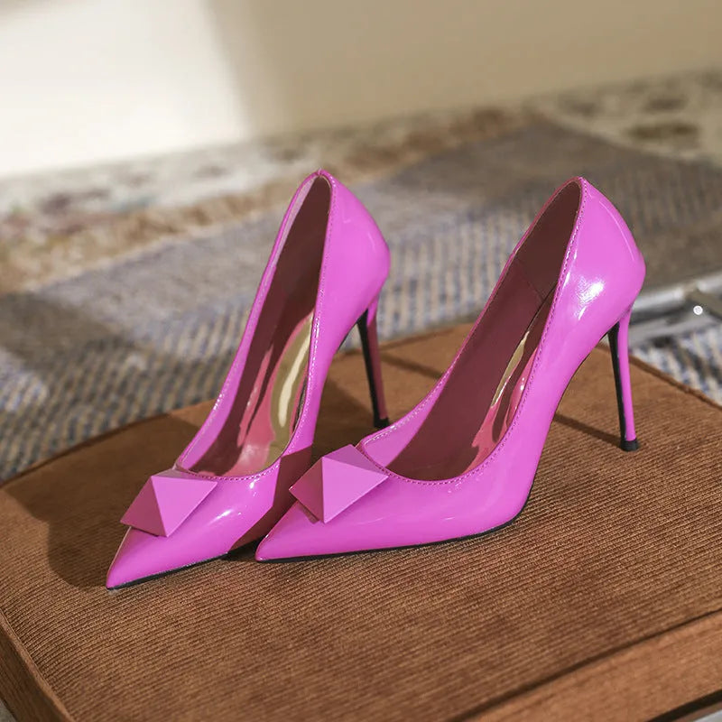 Pink patent leather women's stiletto heels with pointed toe, rivet detail, and an adjustable ankle buckle.