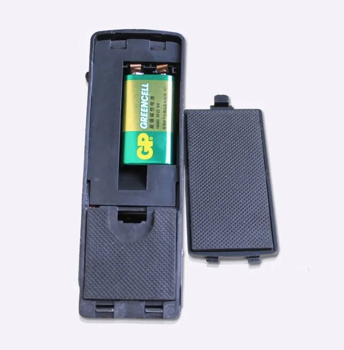 Black portable wedge door alarm with stainless steel cover placed against a hinged door.