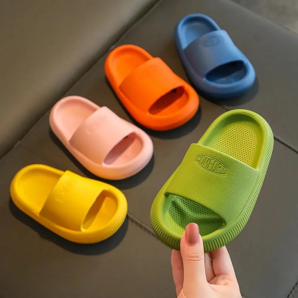 Bright coloured EVA children's house slippers with thick, textured non-slip soles on a wooden floor.