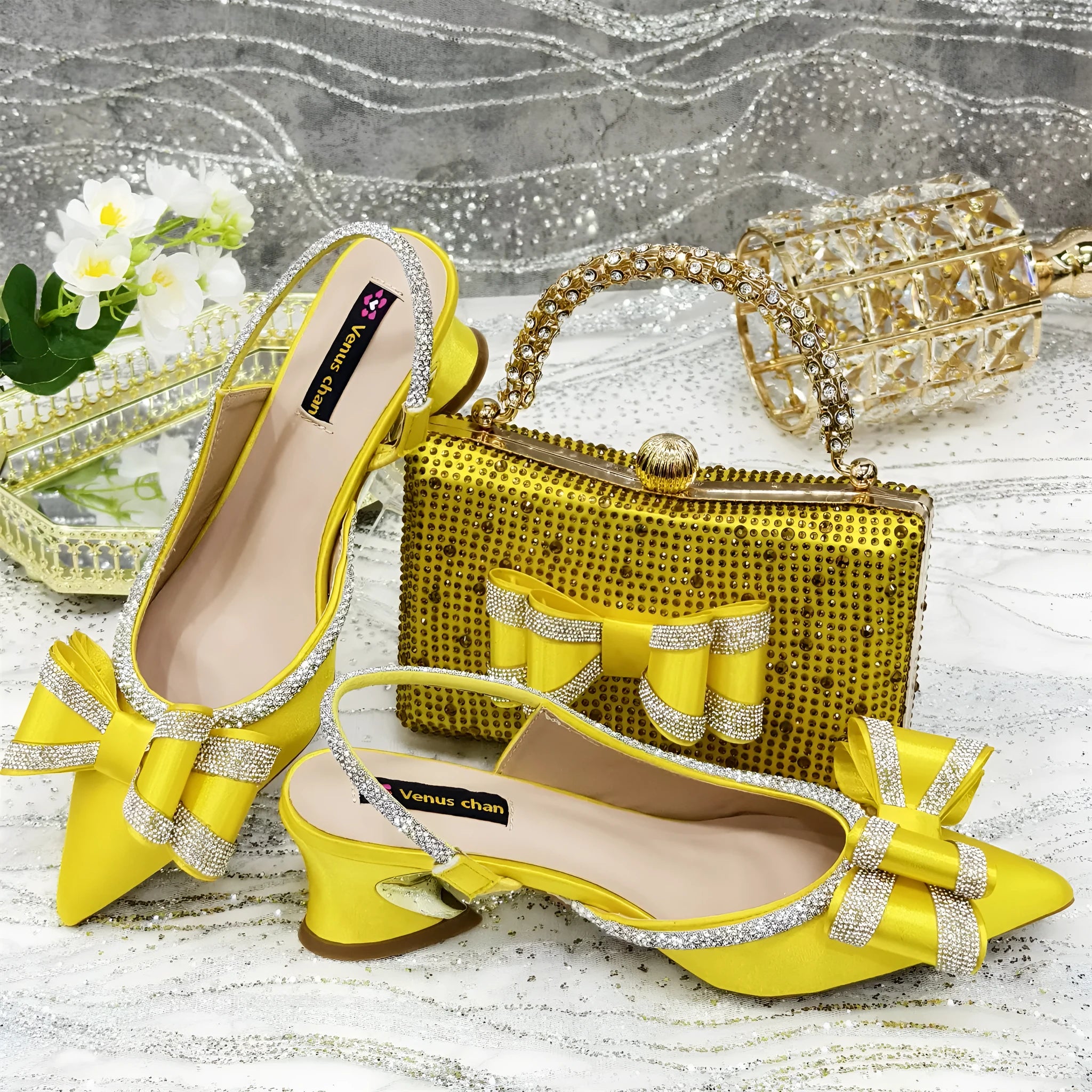 Women's black pointed sandals with mid heel, square rhinestone buckle, elastic band, and matching square bag