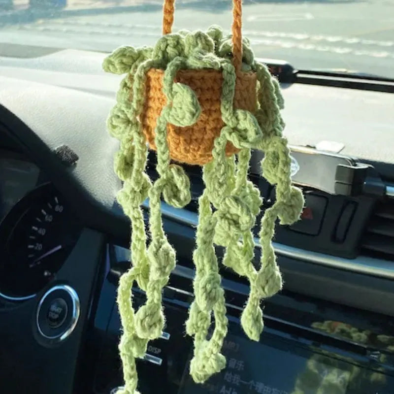Green and white knitted wool car plant ornament hanging from a rope