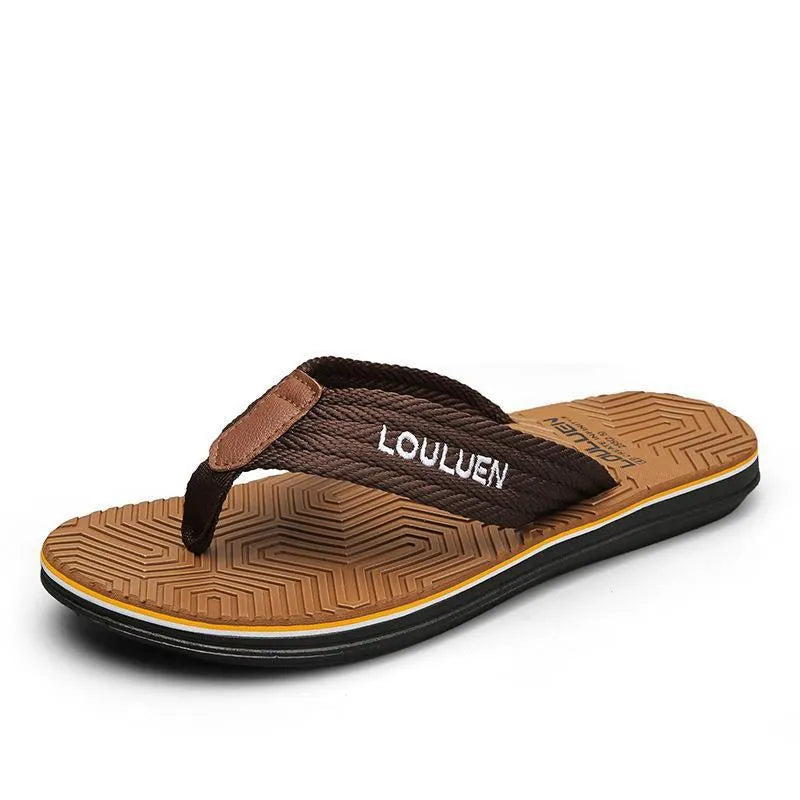 Men's black flip flops with open toe design and textured non-slip sole on a sandy beach.