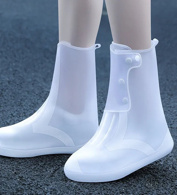 White high-top PVC reusable waterproof shoe covers for women on a wet surface.