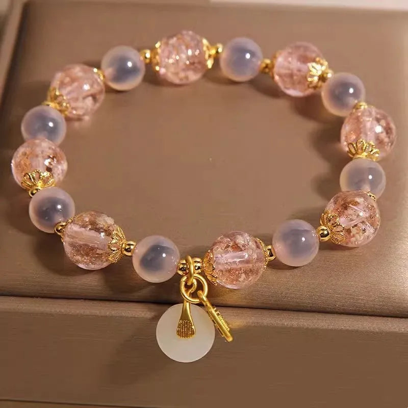 Close-up of a women's pink agate heart bracelet with a luminous glaze and a silver peace buckle clasp.