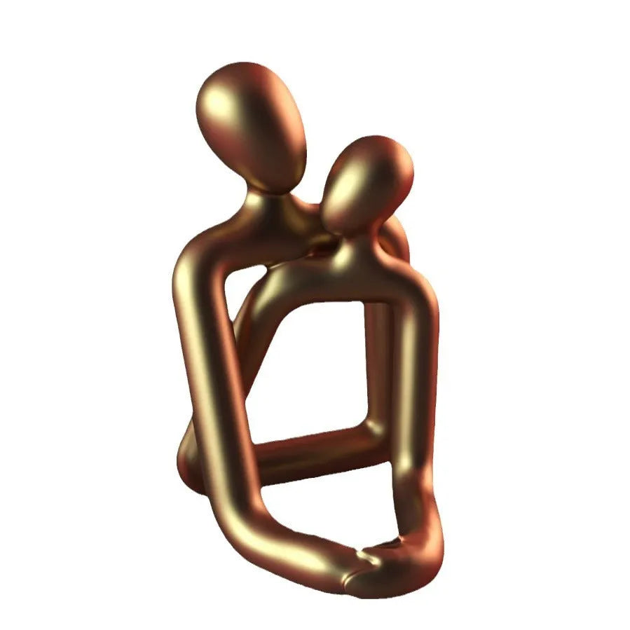 Modern minimalist resin statue of a couple in milky white or gold finish on a wooden surface.