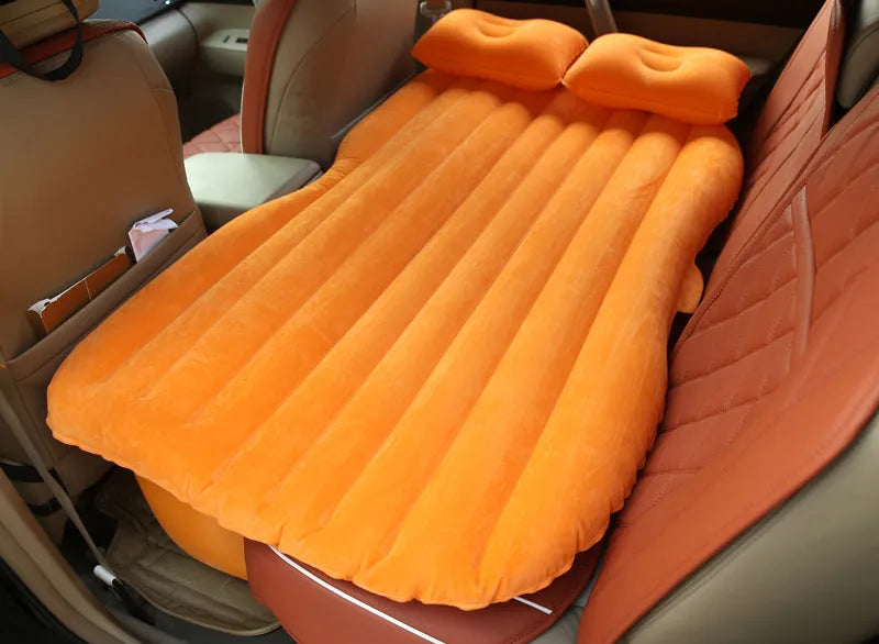 Inflatable car bed with flocked surface and pillows, set up in the back of a five-seater vehicle.