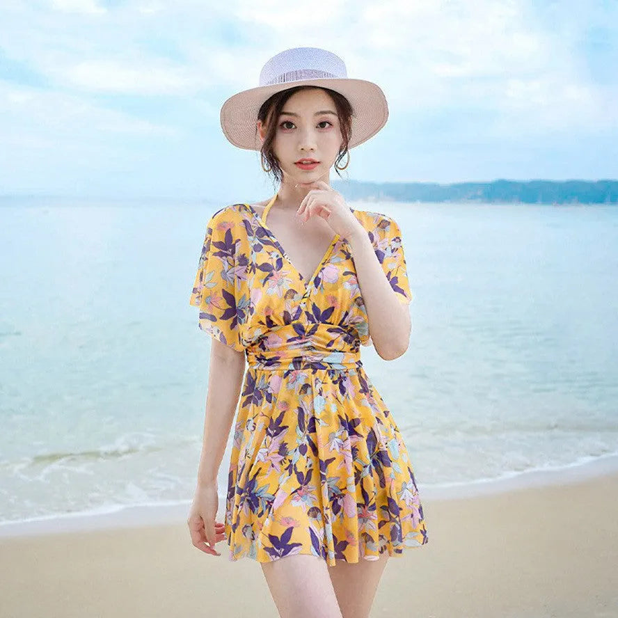 Yellow floral print women's one-piece swimsuit with skirted design.