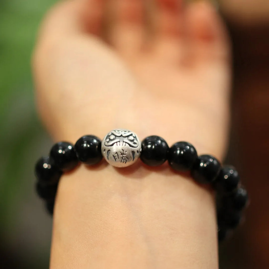 Close-up of a women's bracelet with large black agate beads and a sterling silver clasp on a wrist.
