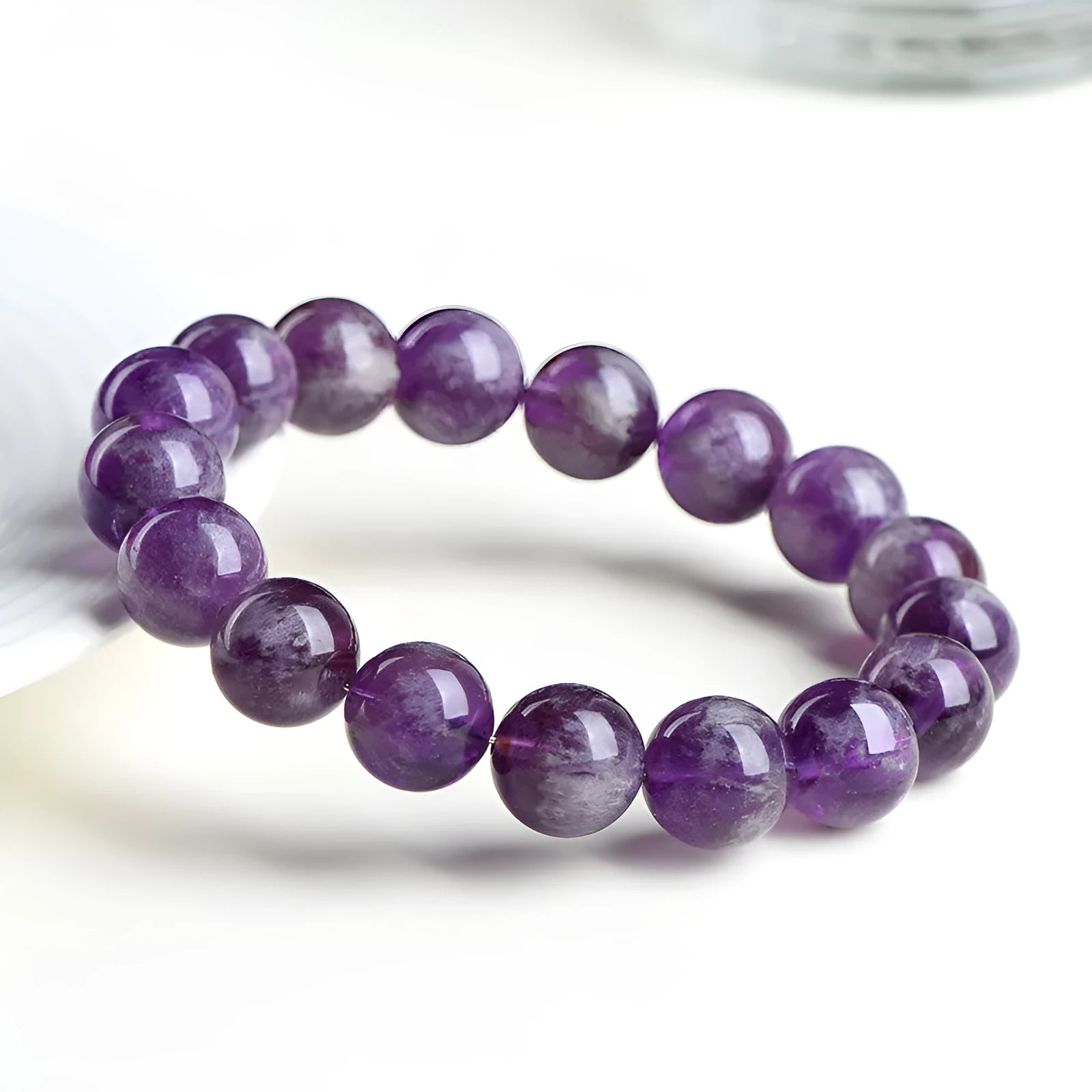 Natural feather amethyst crystal bracelet with scattered geometry beads and Ruyi element on a wrist.
