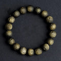 Obsidian crater ball bracelet on a wrist, showing ground stone texture and bead size.