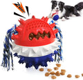 Blue and red ball-shaped dog chew toy with rope and treat dispenser hole on green grass