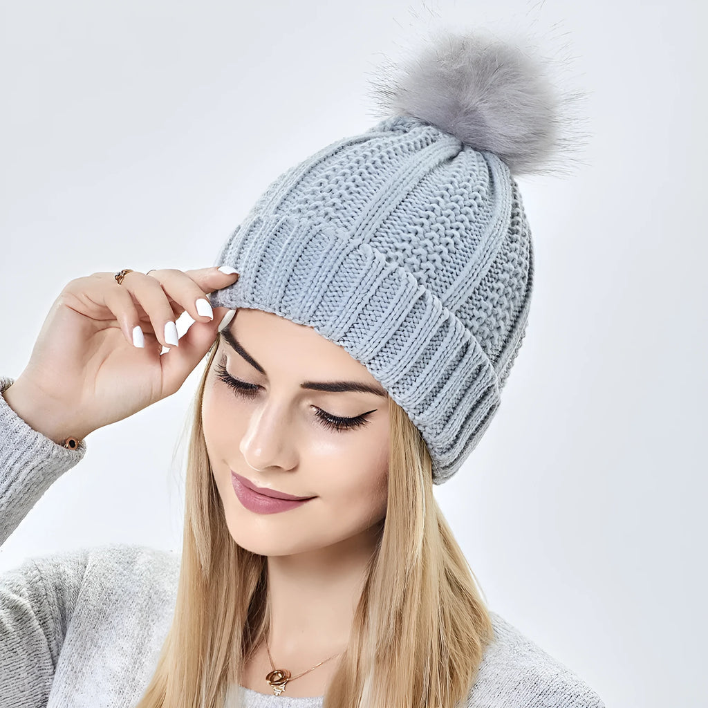 Women's knitted beanie hat with faux fur pom pom in wine red, showing satin lining interior.