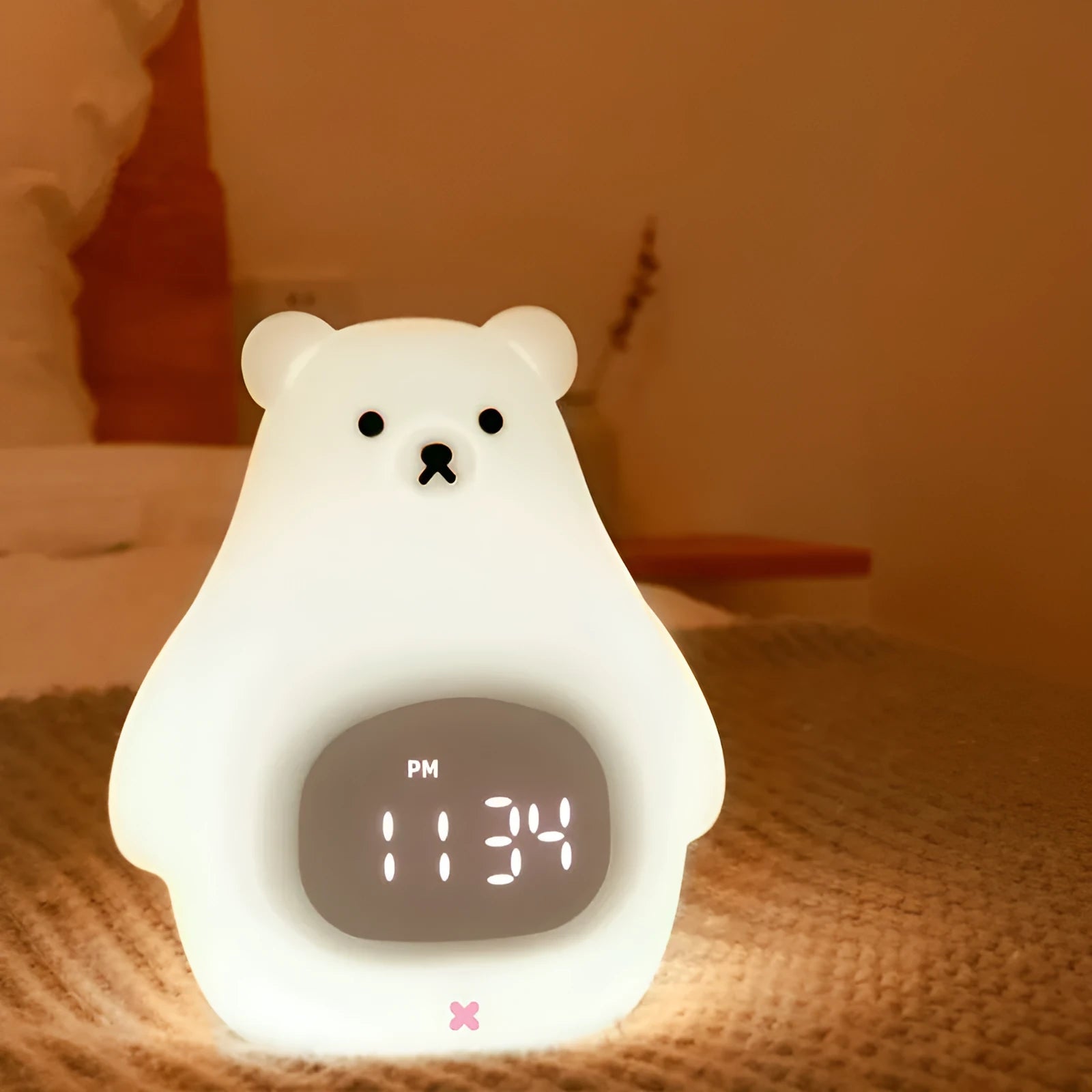 White silicone bear-shaped night light with remote control on a wooden bedside table.