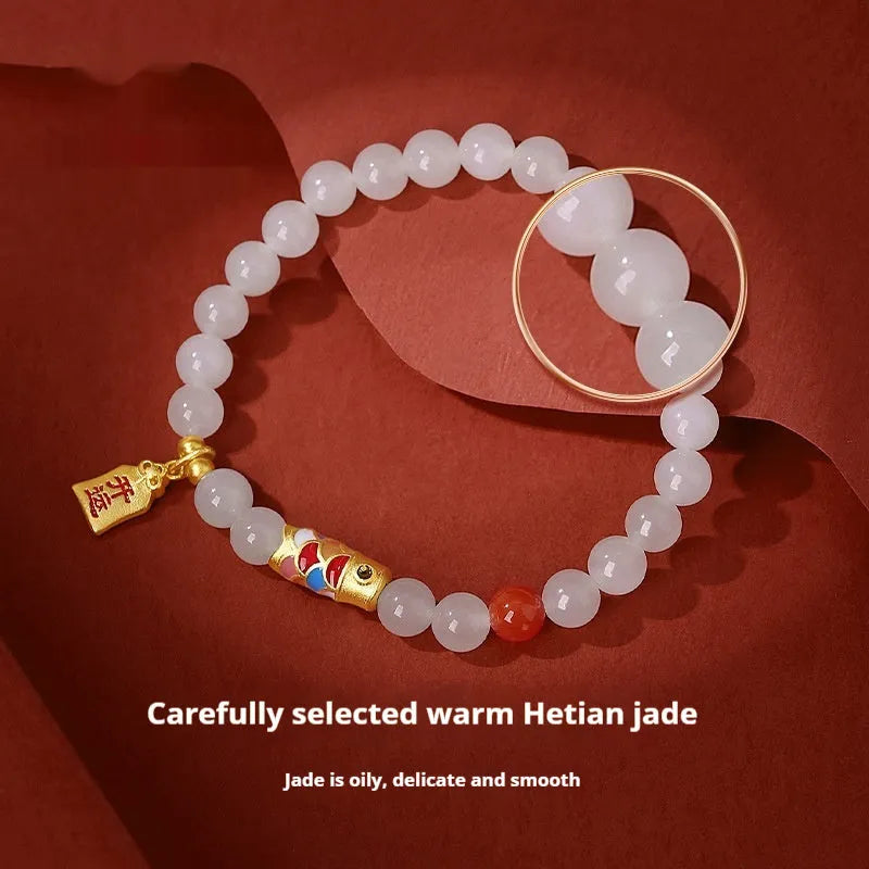 Close-up of a sterling silver bracelet with a carved green Hetian jade koi fish charm.