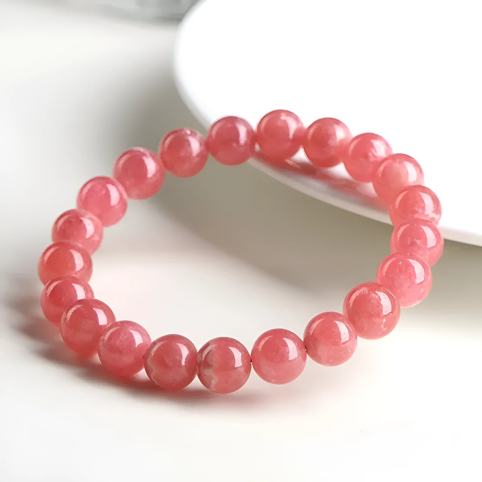 Close-up of a red rhodochrosite crystal bracelet with geometric beads and a Longevity Lock clasp.