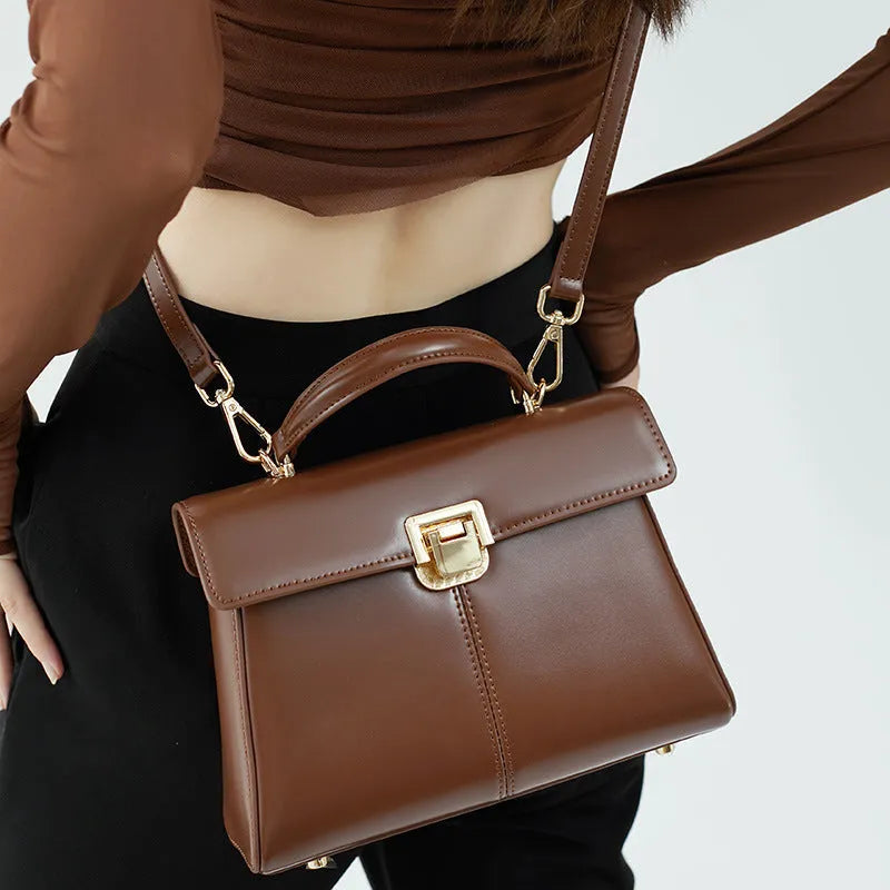 Women's black genuine vachette leather shoulder bag with clasp closure and 120cm strap.