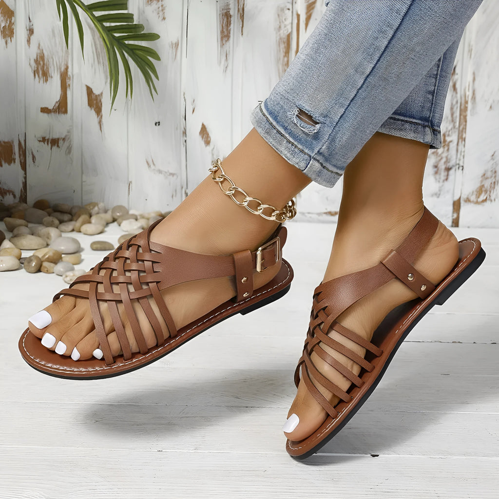 Black Roman style open-toe beach slippers with a cross strap and flat buckle closure.