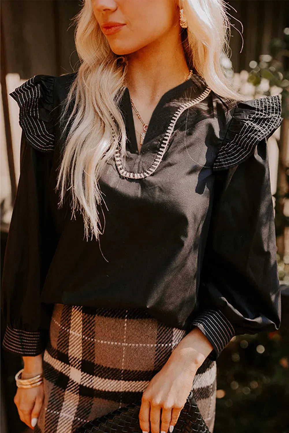 Black women's V-neck long sleeve blouse with ruffle trim and contrast stitching detail.